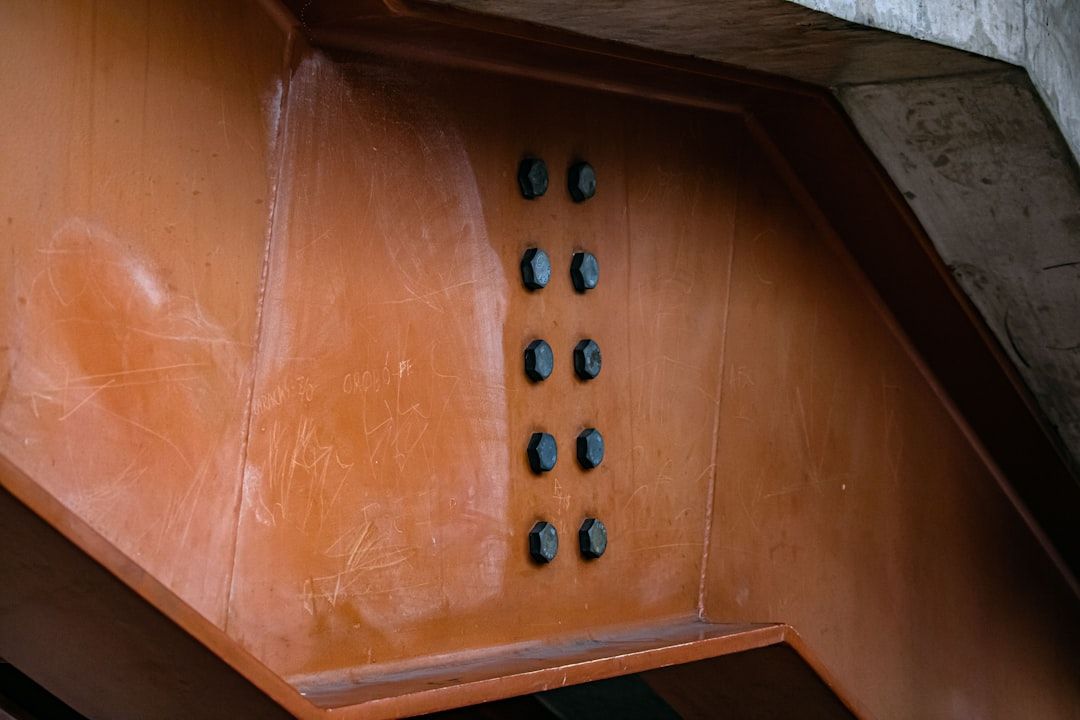 Industriella bultar på en orange stålbalk som påminner om moderna svarta handtag.